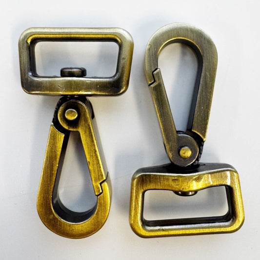 Two brass-colored metal hooks on a white background