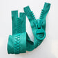 Teal-green molded plastic zipper with chunky teeth, oversized round ring pull, and textured herringbone tape