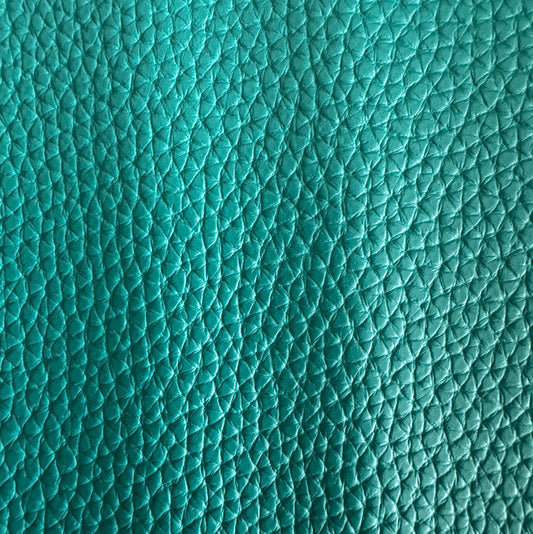 Close-up of a vibrant teal pebbled leather texture, showing a detailed pattern of fine, shimmering creases and raised bumps that capture the light.