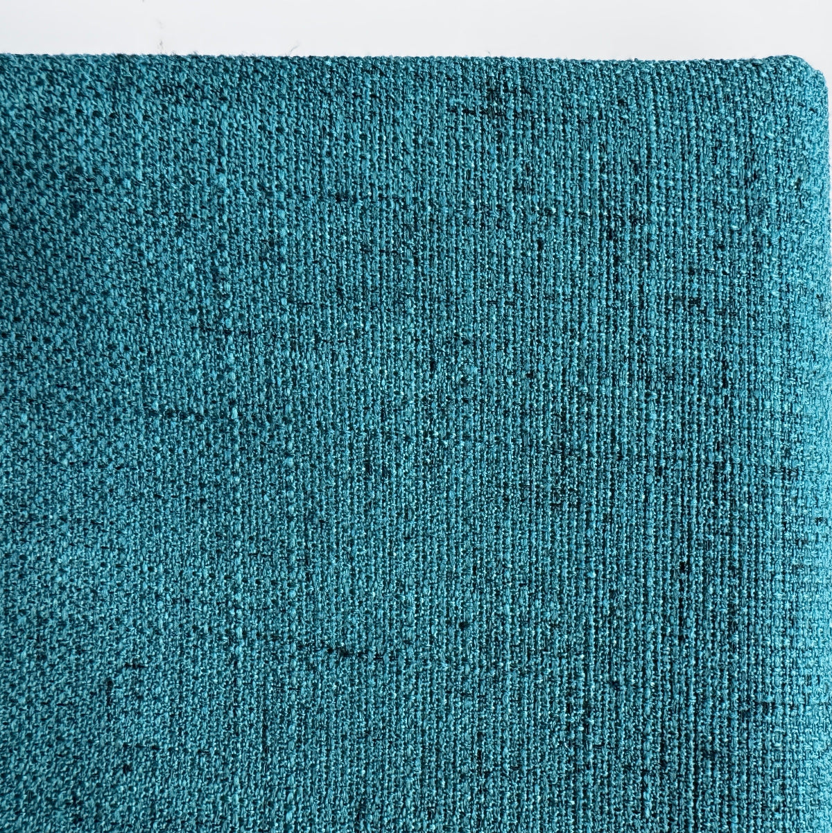 A close-up of a textured fabric or material swatch in a teal blue-green color with subtle darker flecks, shown against a plain white background.