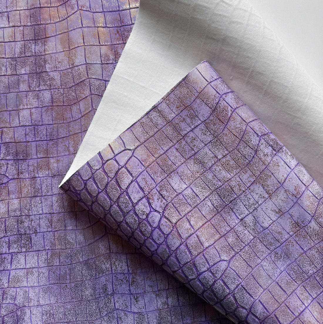 Close-up of textured purple fabric with grid pattern on a neutral background