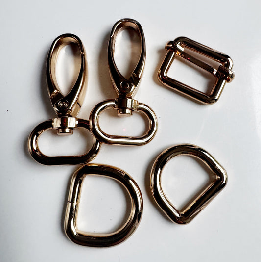 3/4 inch gold bag hardware set including swivel lobster clasps, D-rings, and an adjustable strap slider on a white background