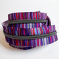 A coiled zipper with a vibrant, multicolored striped fabric tape and a dark metallic zipper track, shown on a plain white background.