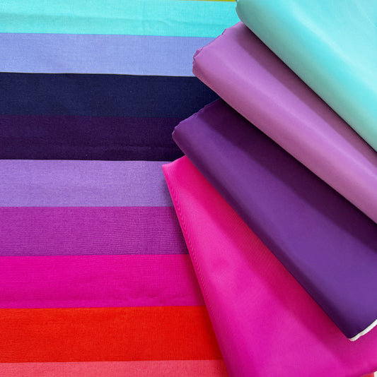 Stack of colorful fabric swatches in various bright colors.