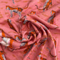 A high-angle, close-up shot of soft pink rayon fabric patterned with stylized orange-and-black tigers and wavy horizontal lines.