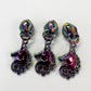Three matching iridescent metallic unicorn-shaped zipper pulls or pendants arranged side by side on a plain white background.