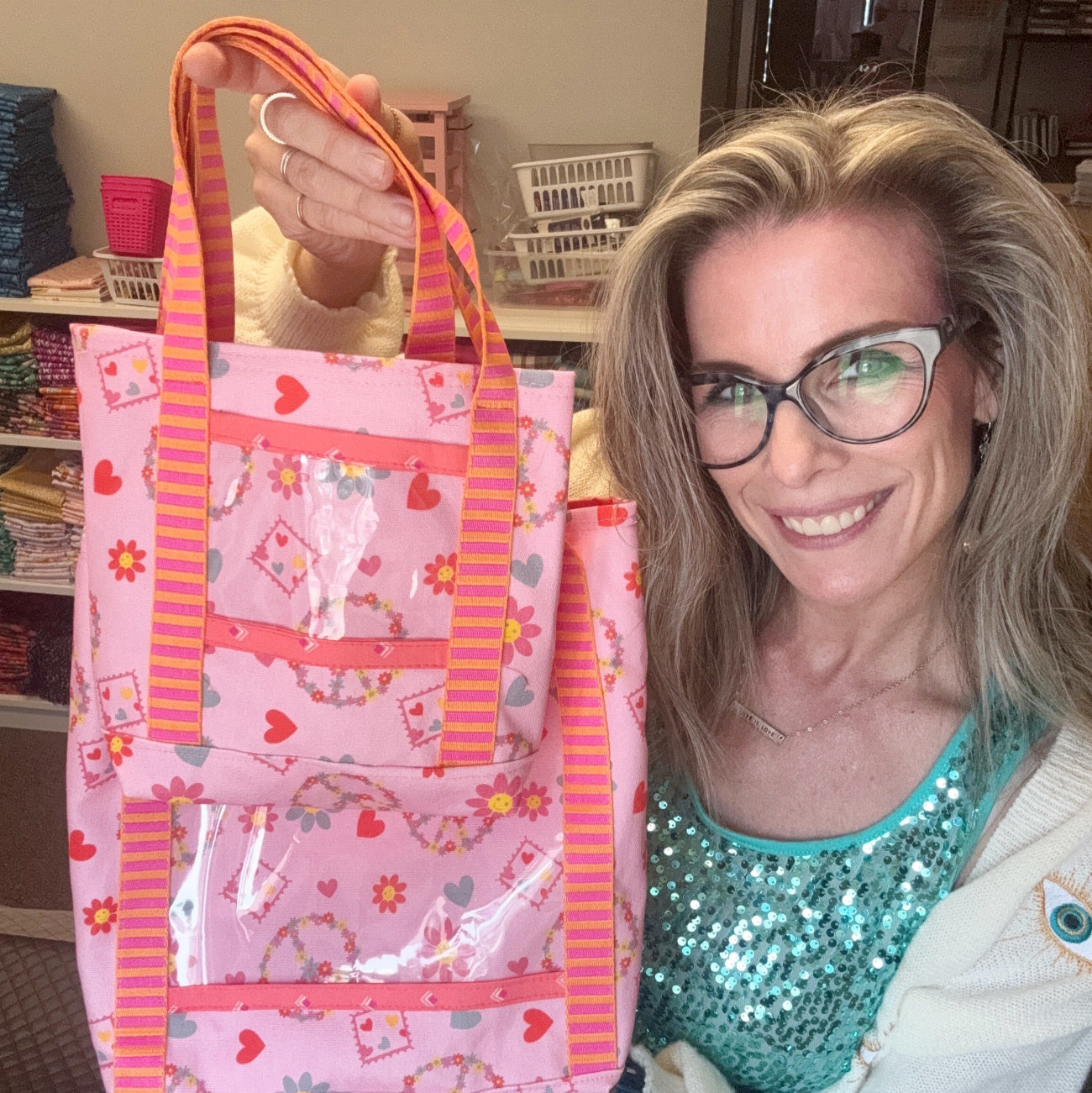 Finished Valentine's tote bag with clear vinyl pockets, pink heart print fabric, and striped webbing handles displayed by the maker.
