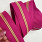 Close-up of pink zippers with gold trims held by a hand on a white background