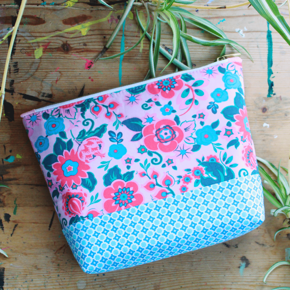 Pink and blue floral pouch on wooden surface.