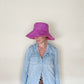 Woman wearing a structured magenta bucket hat, denim shirt, leopard-print top, and teardrop earrings