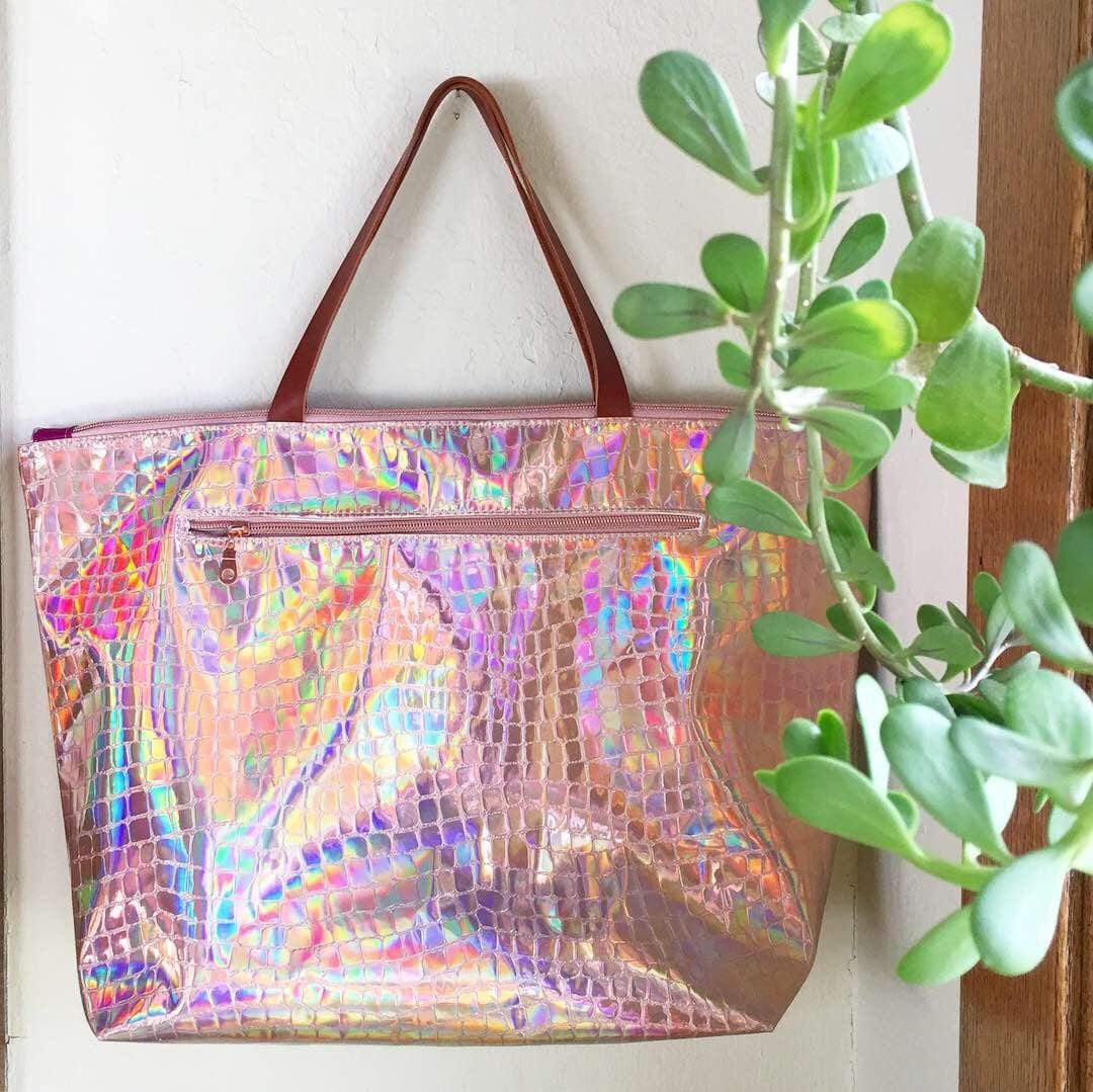 Holographic tote bag (3AC67271) with brown handles, next to plant.