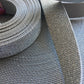 Spool and strip of gray woven fabric.