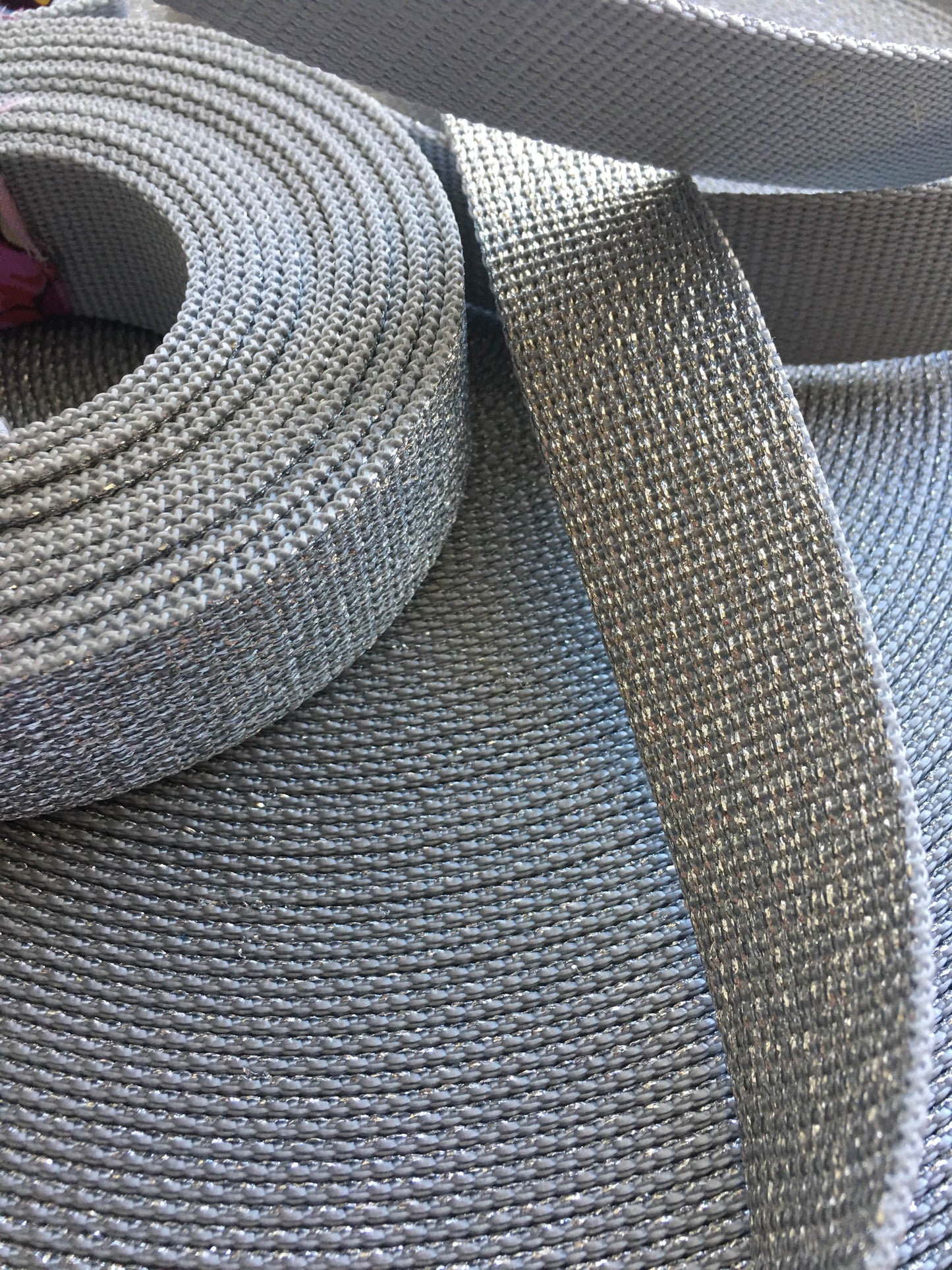 Spool and strip of gray woven fabric.