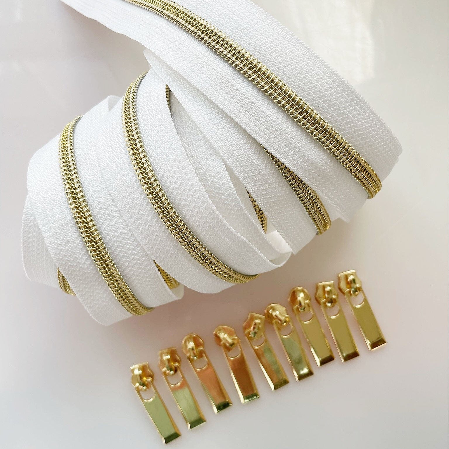 White zipper tape with gold teeth and pulls.